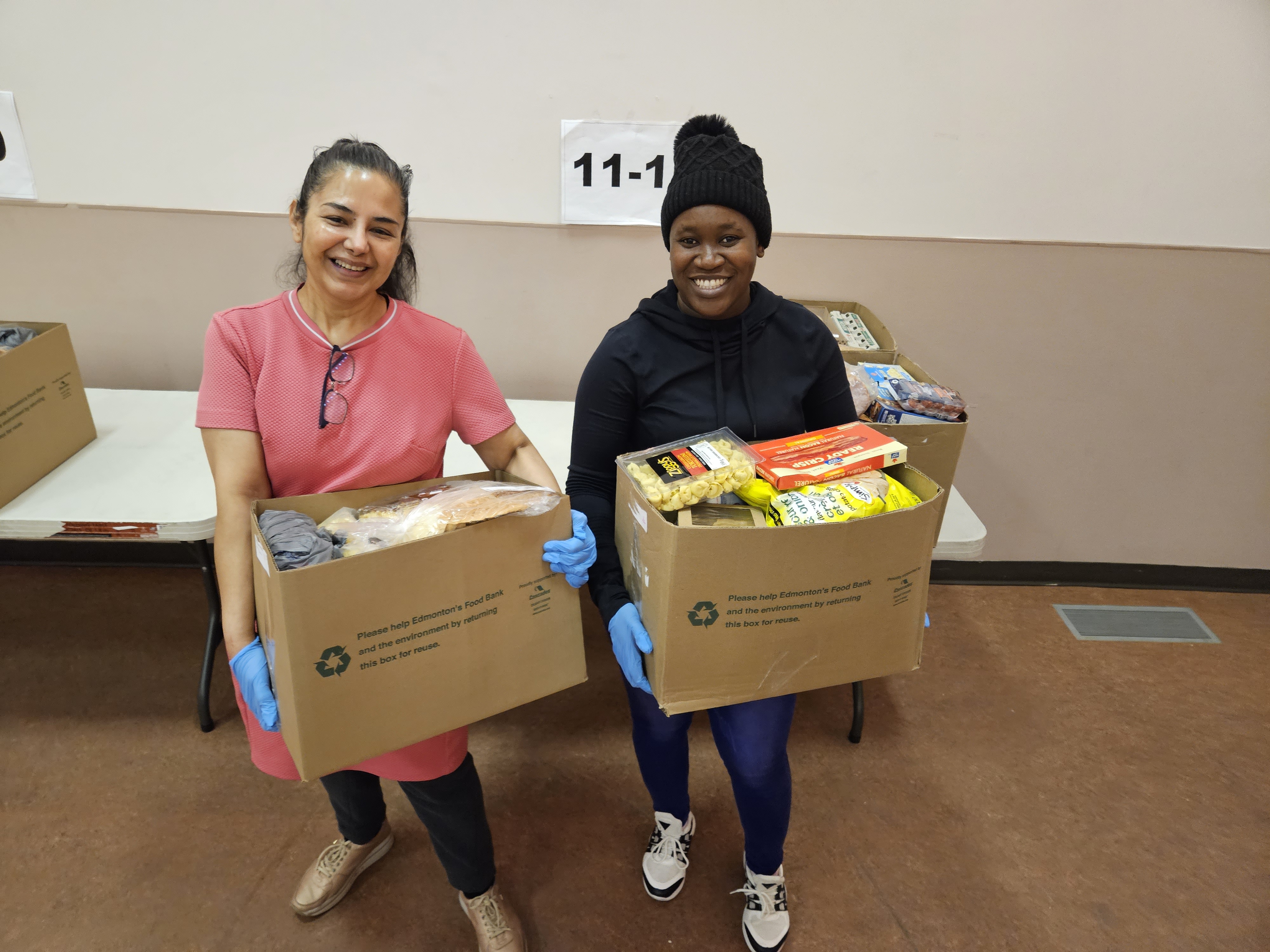 Two people holding Christmas Hampers and smiling at the camera